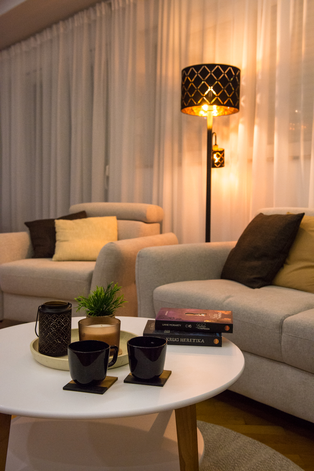 Two coffee cups and books arranged on the round living-room table beside the sofa