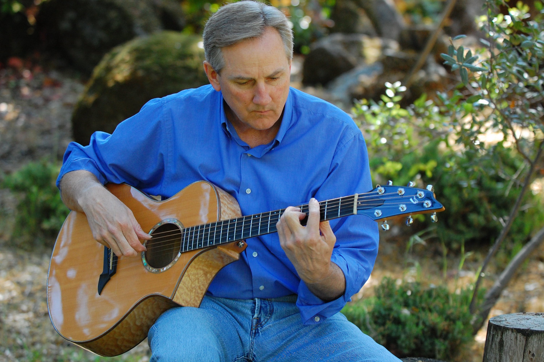 Kyle Freeman playing his acoustic guitar in a garden