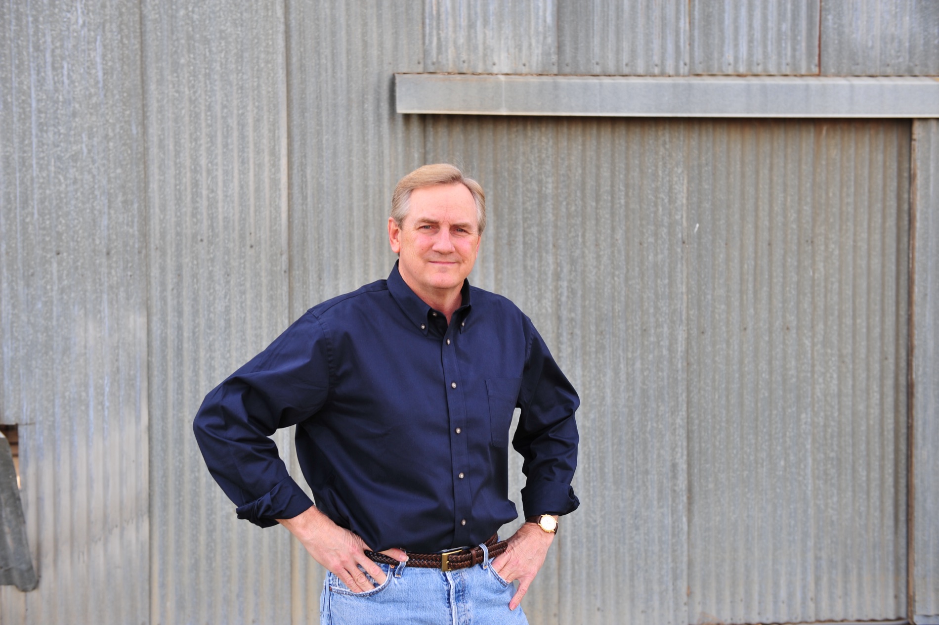Kyle Freeman standing with his hands on his hips in front of a weathered metal wall