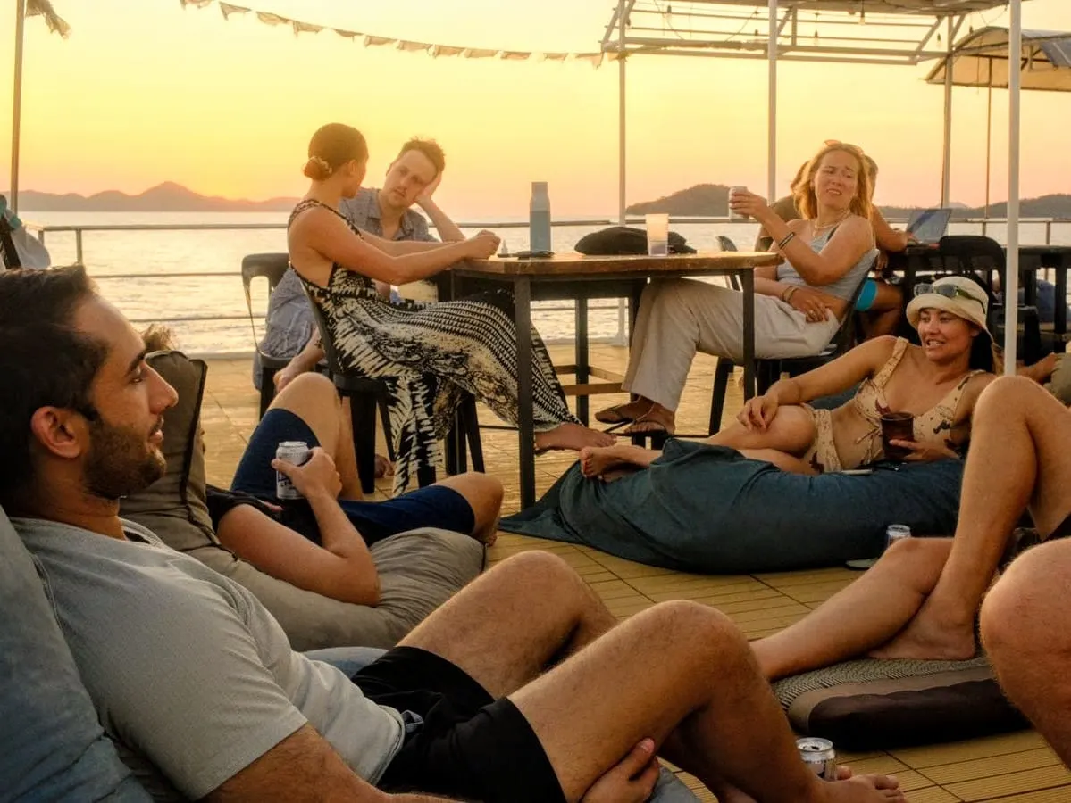 Plongeurs au repos sur le pont d'un bateau au coucher du soleil