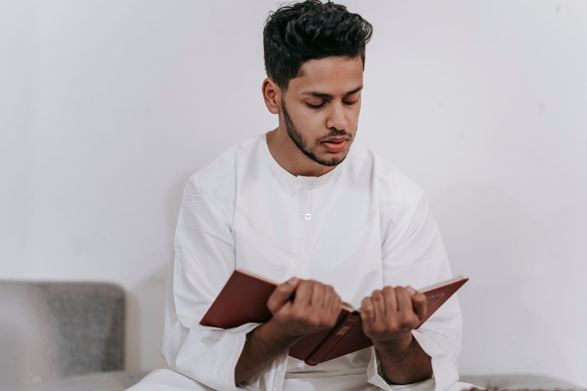 A community member reading Qur'an with focused attention.