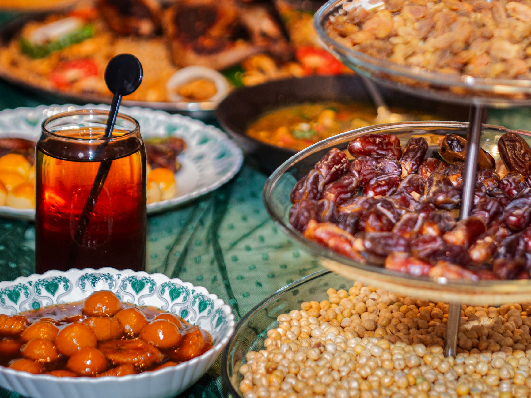 A long table set for a community iftar, lit by lantern light.