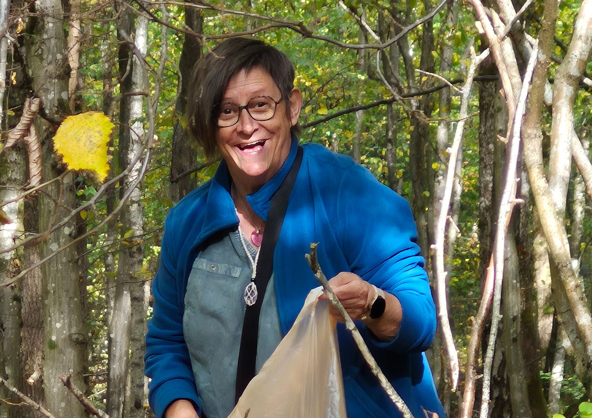 Anne lacht in het herfstbos, met een tak in de hand