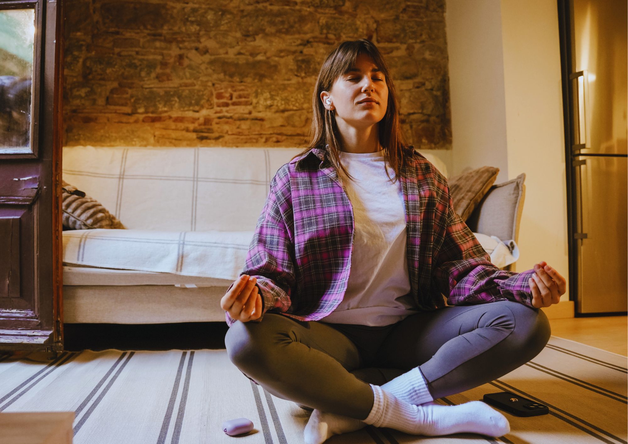 Jonge vrouw zit met gekruiste benen op de vloer te mediteren