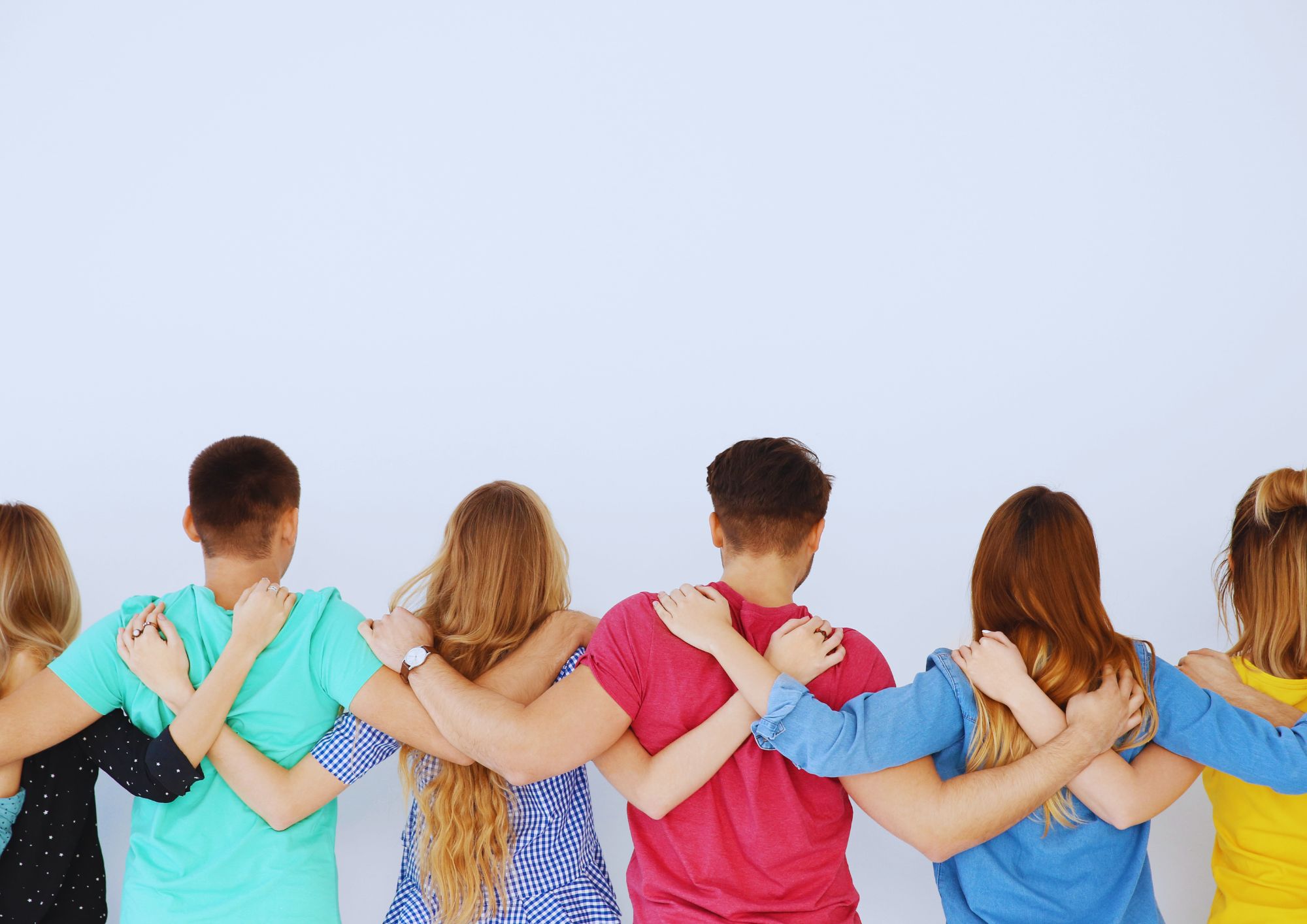 Groep jongeren staat arm in arm, van achteren gezien