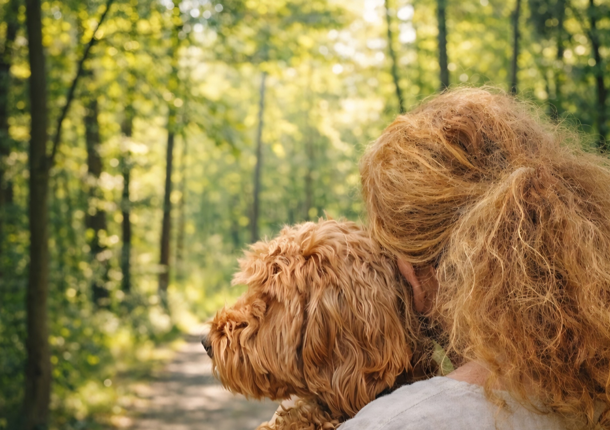 Patricia van achteren gezien met haar hond op een zonnig bospad
