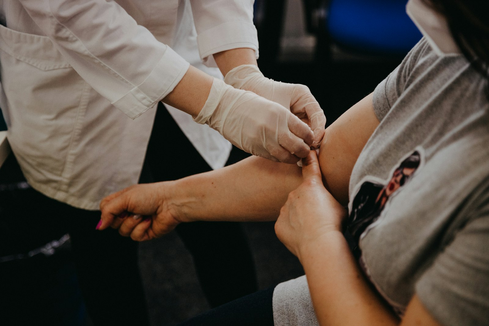 Clinician in gloves preparing a patient's arm for a blood sample