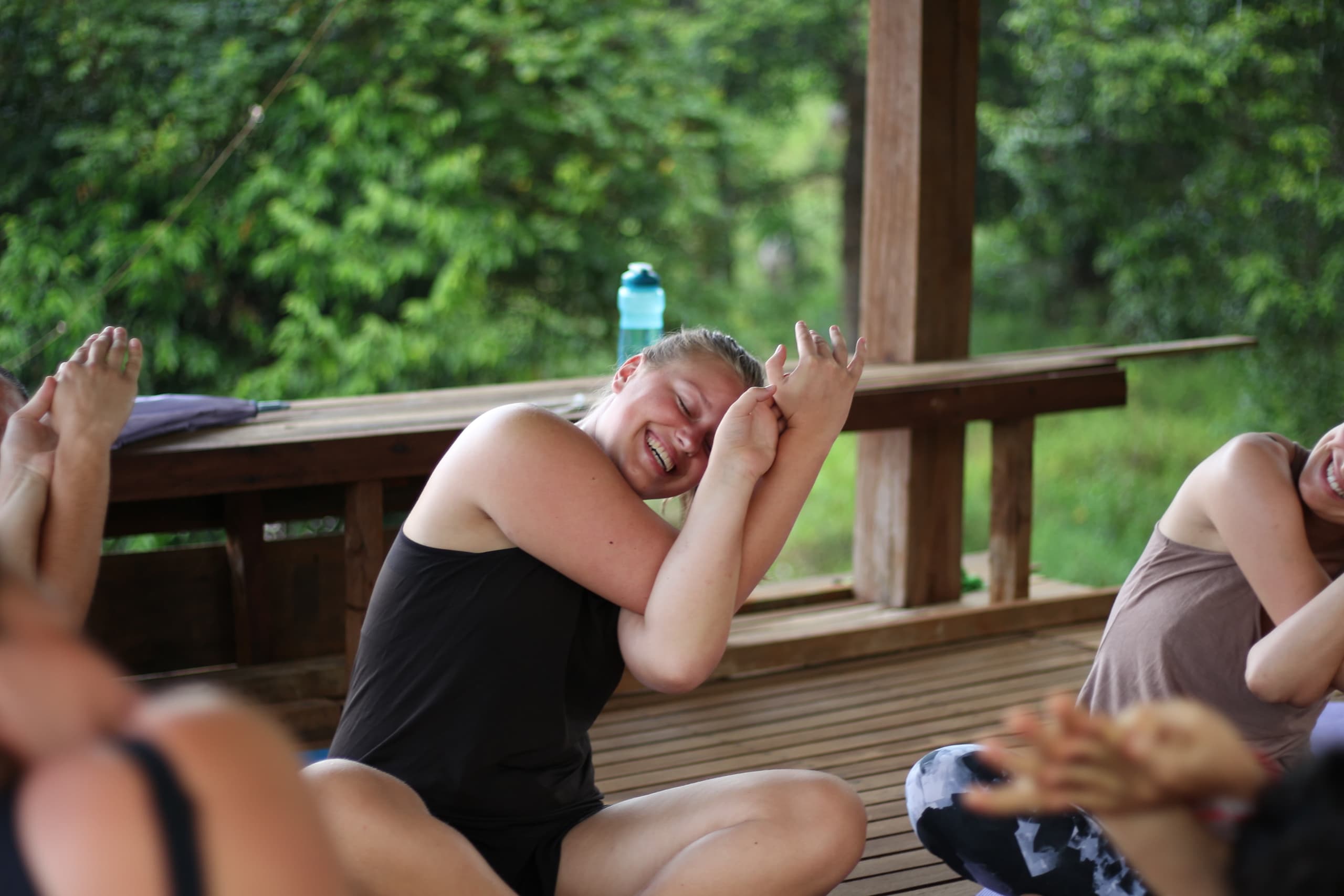 A woman stretching and smiling with a jungle background
