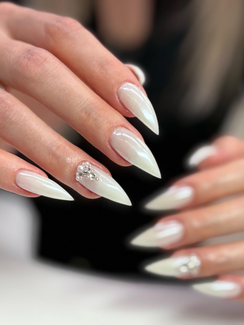 Milchig-weisse Stiletto-Nägel mit Perlen und Strass