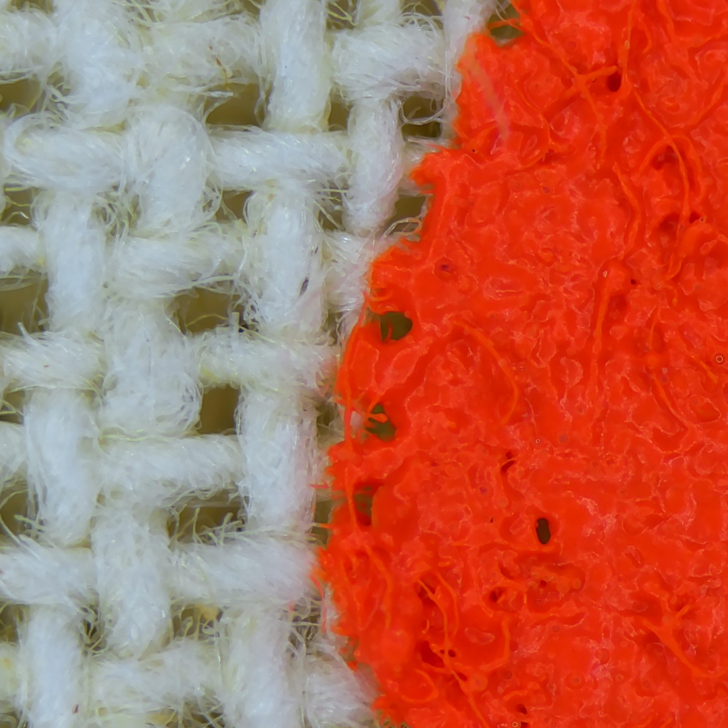 Real held-out microscope photograph showing individual white and orange tote fibres