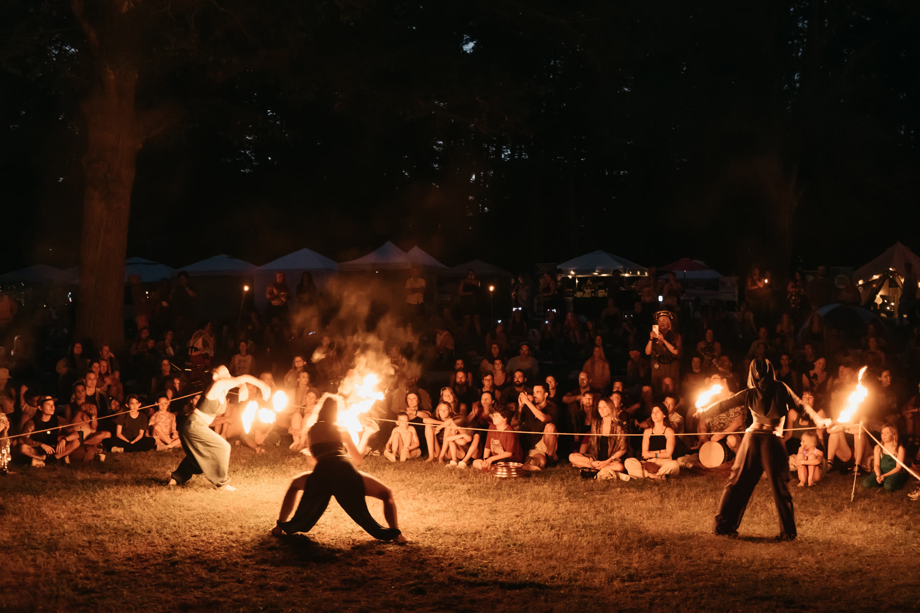 Symbiotica performers moving with fire before a gathered community