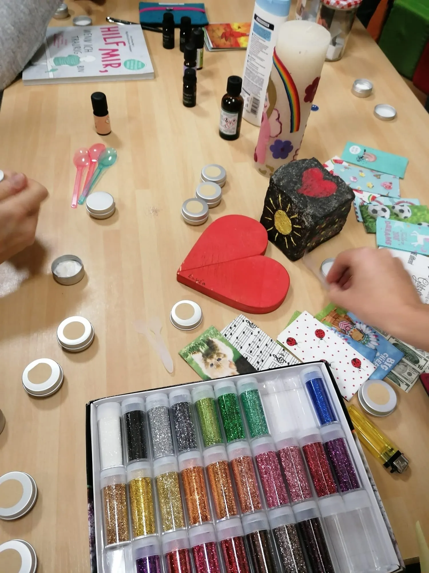Tisch mit Glitzer, Holzherz und Materialien aus einem Kreativworkshop