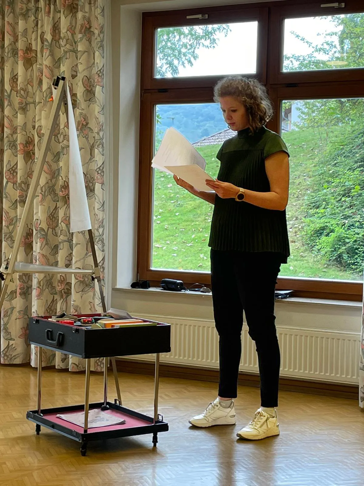 Jennifer Otte mit Unterlagen vor Flipchart und Materialwagen