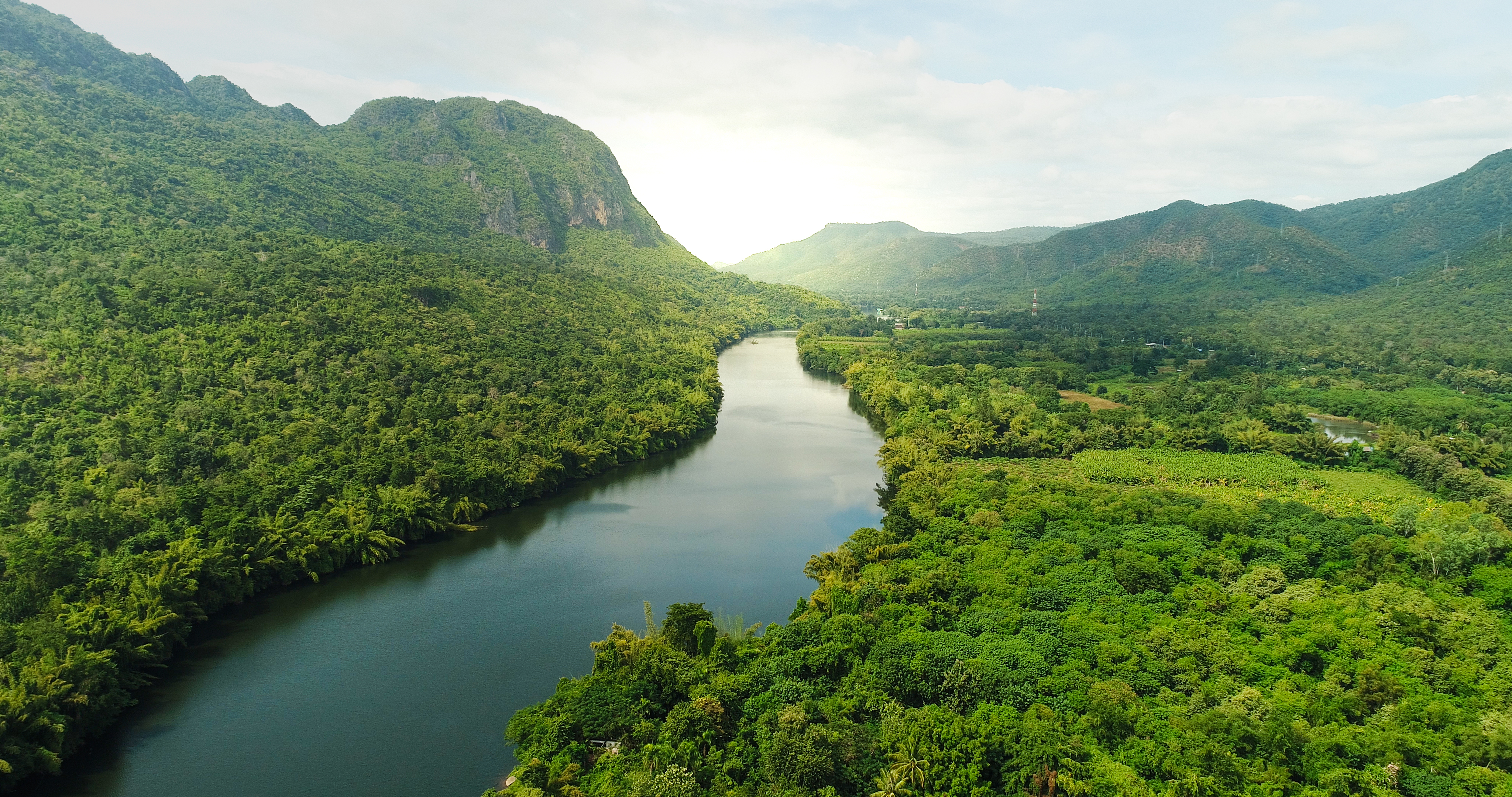 river in the middle of green fields and mountains