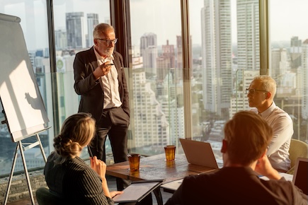 banker standing up leading a professional meeting