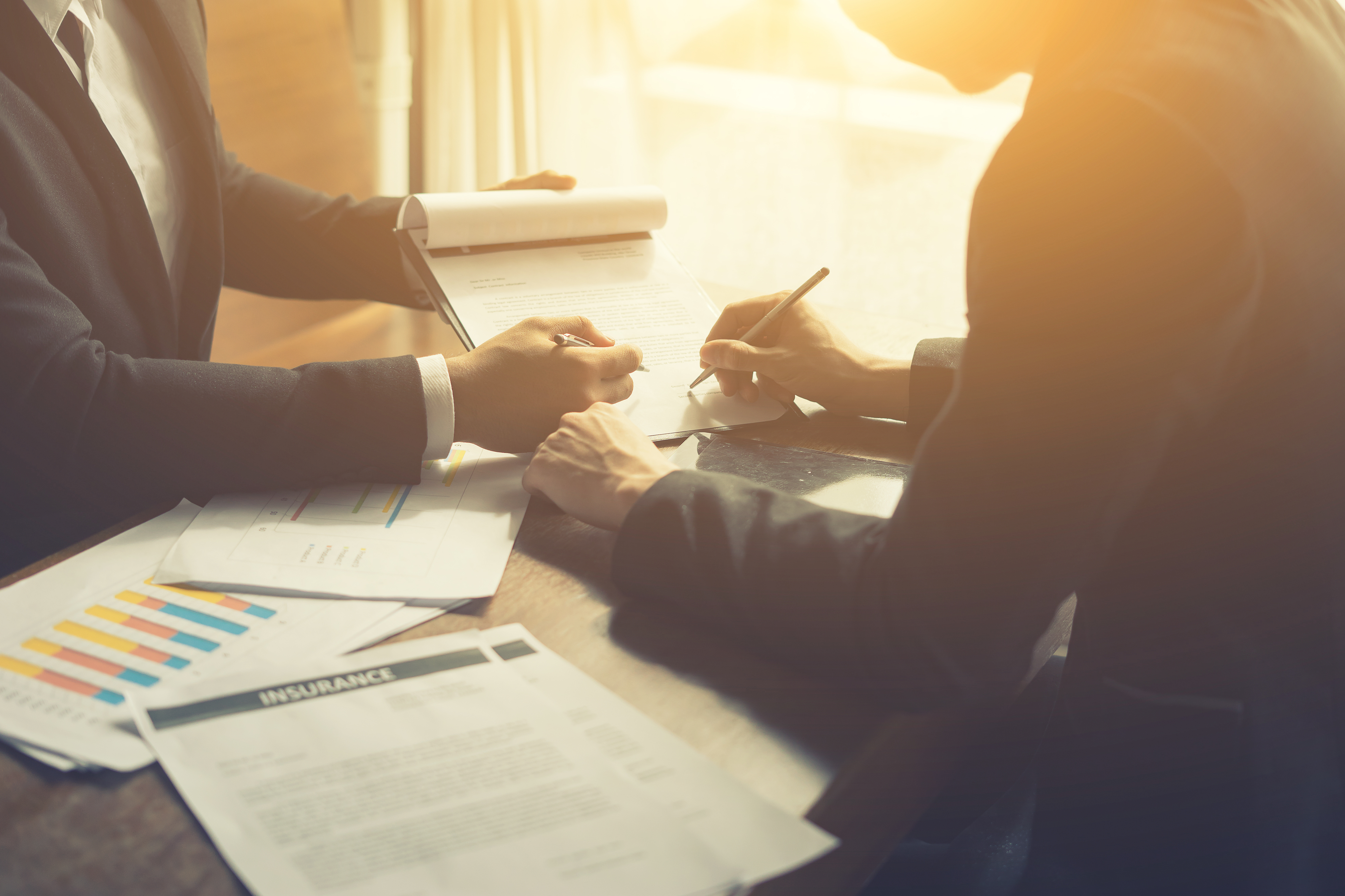two business men signing contracts sitting at a table