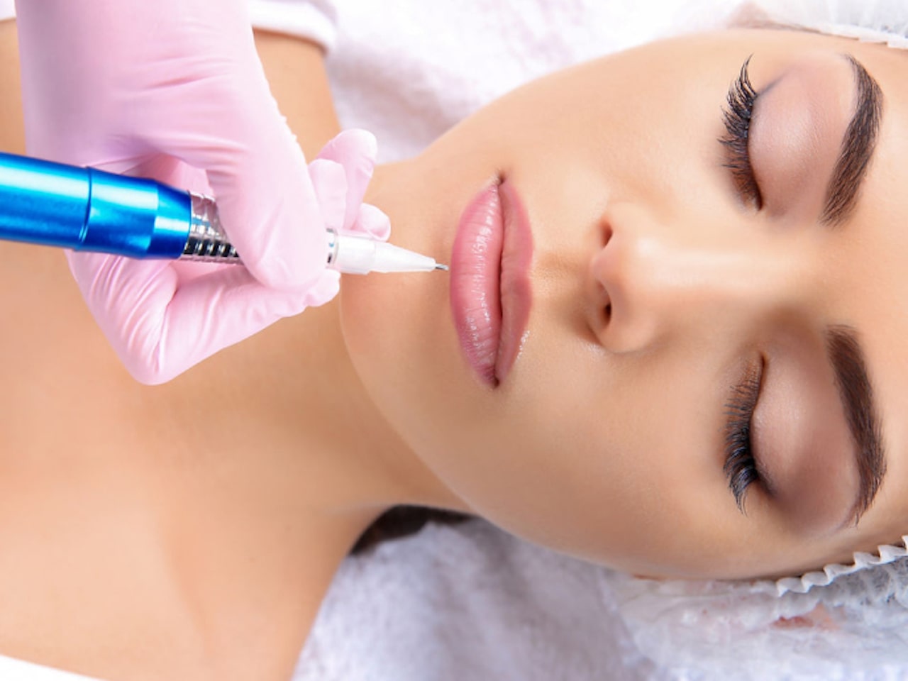 Woman lying down whilst her lip blush technician in Chigwell Essex is blushing her lips.