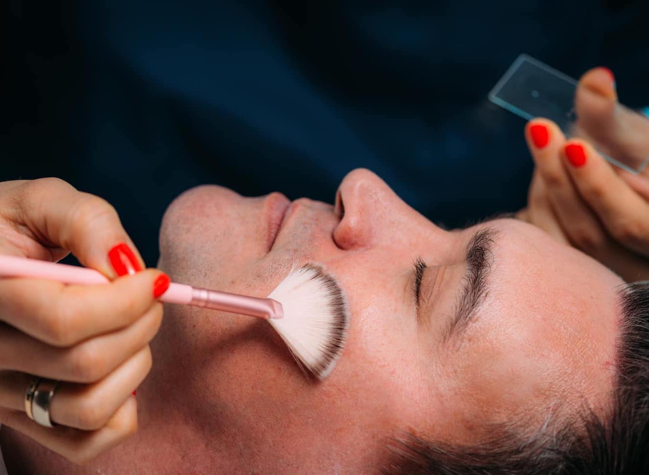 Man lying down with his eyes closed whilst he receives a mens facial in Chigwell Essex.