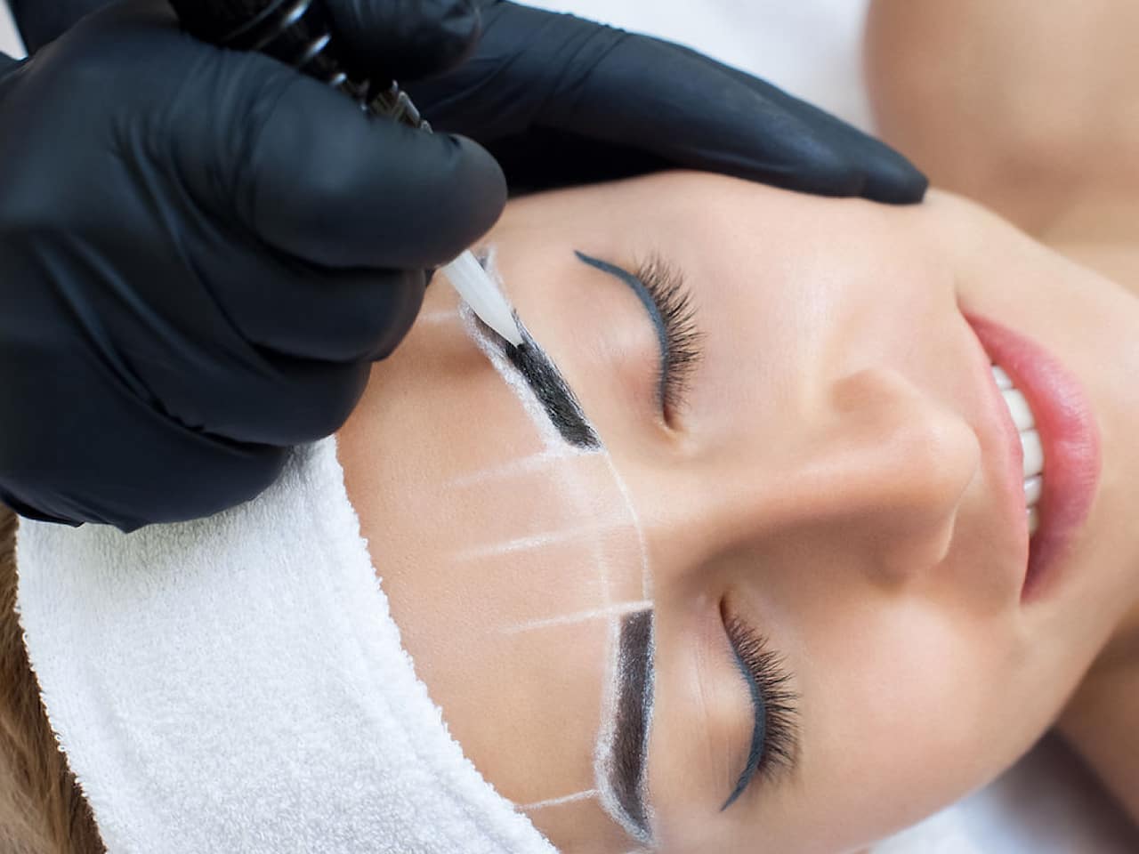 Woman with her eyes closed whilst her microblading technician based in Chigwell Essex maps out her eyebrows ready for tattooing.