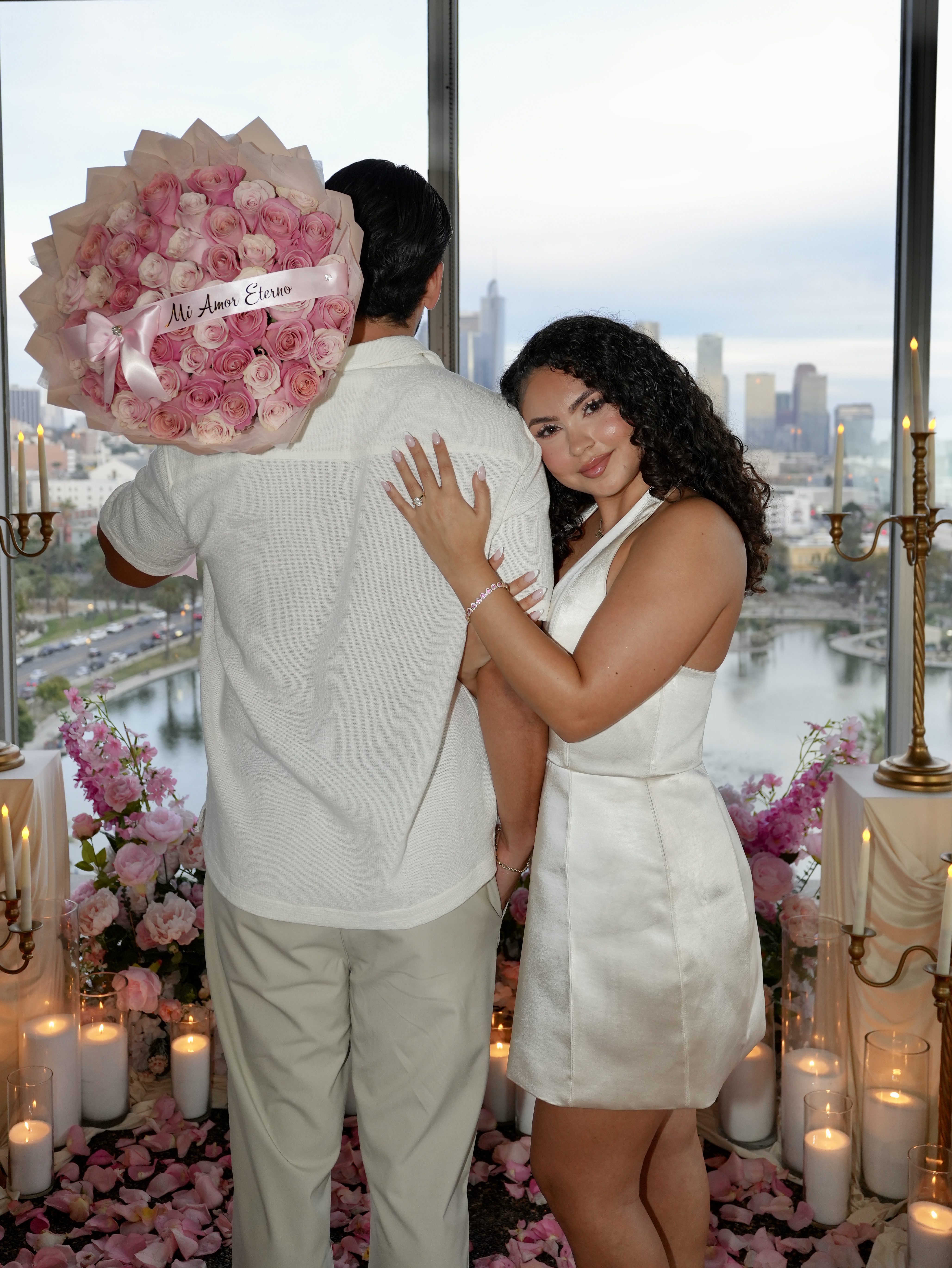 Couple surrounded by lush white and pink florals, flowing drapery, classical columns, and a petal-lined aisle.