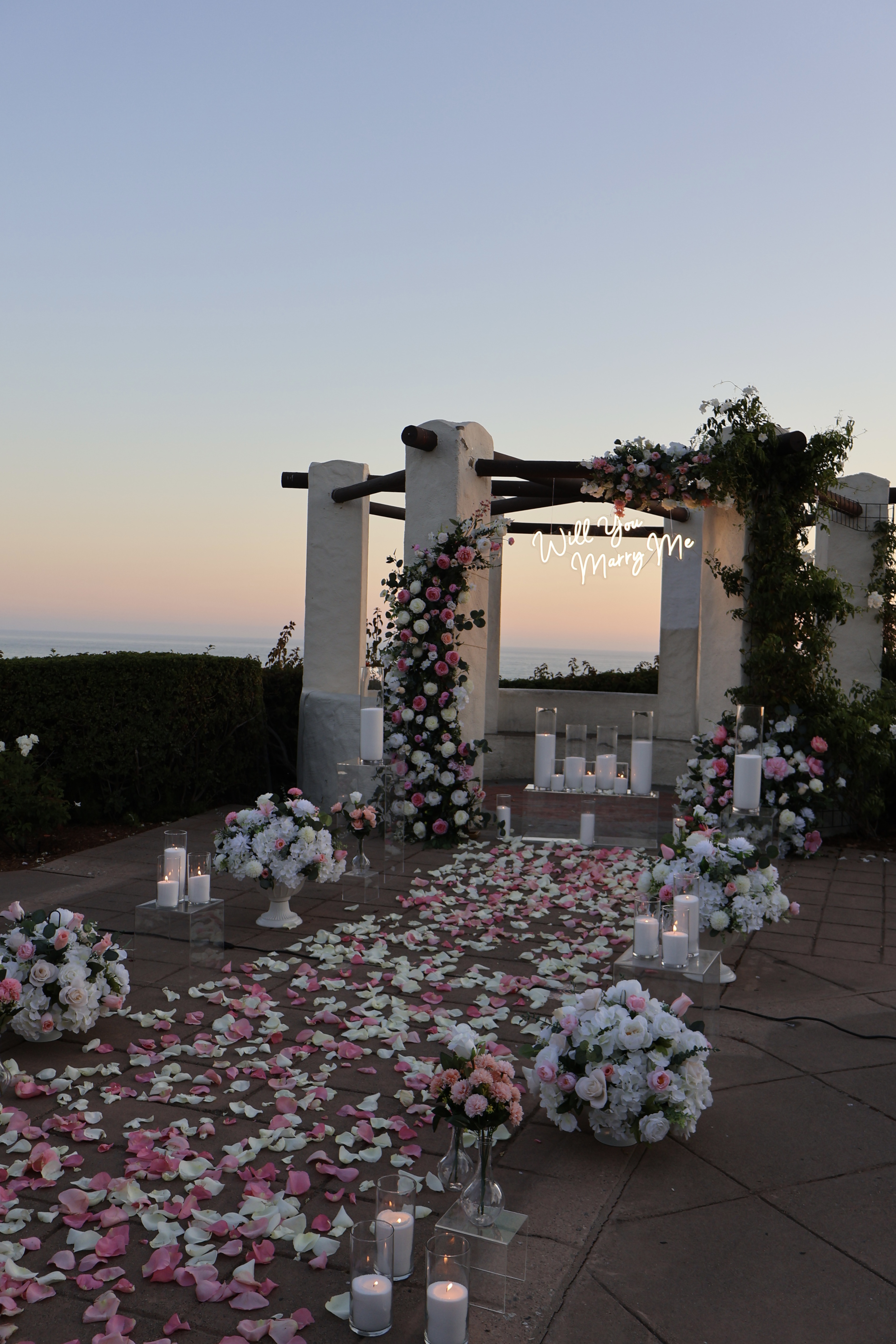 Pink and white proposal at a white gazebo