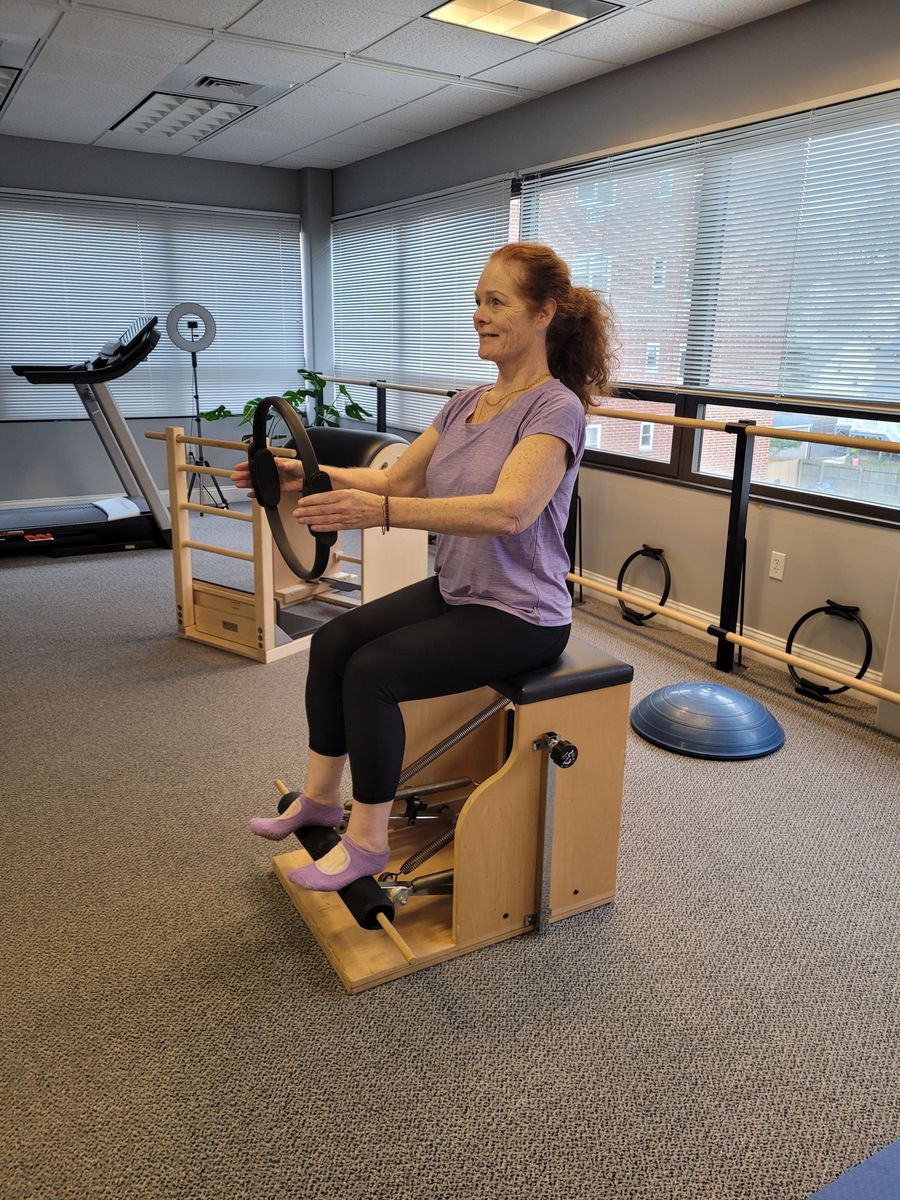 A client exercising on a Pilates chair with a ring