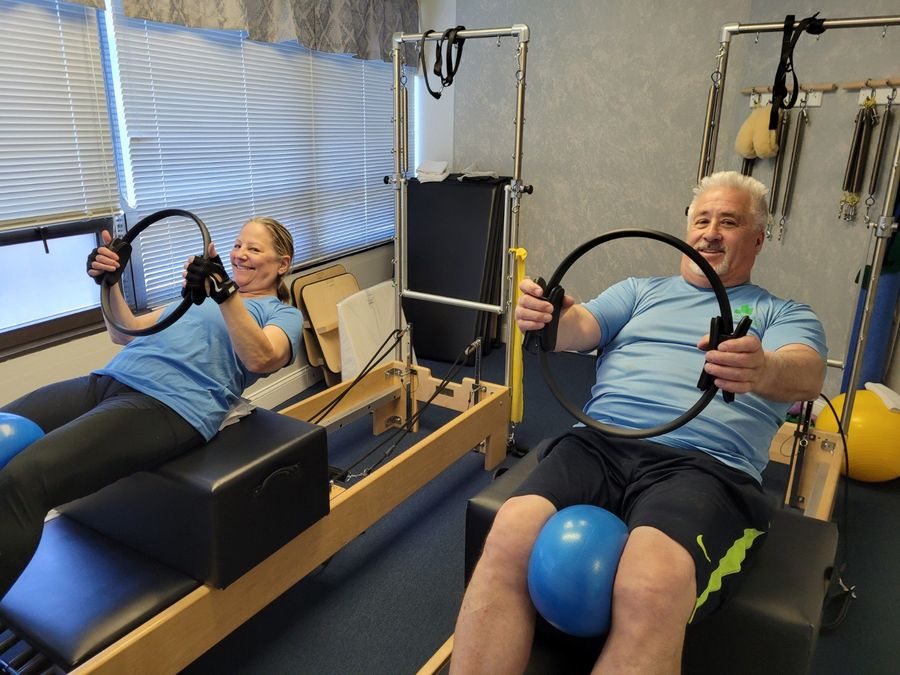 Two clients in a duet Pilates session with Pilates rings