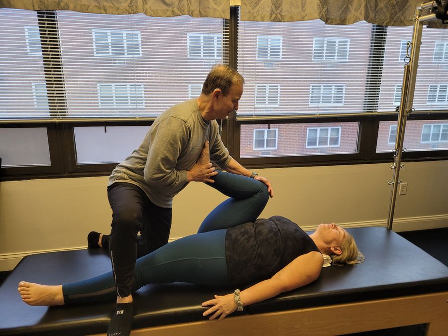 An instructor giving a client an assisted leg stretch