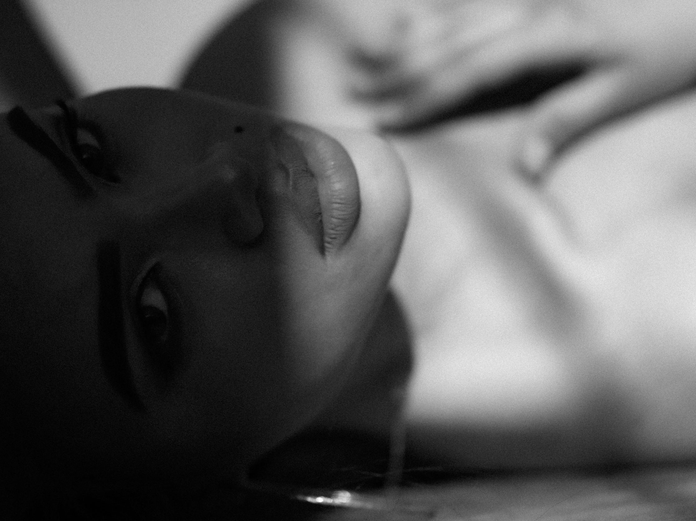 Black-and-white close-up of a woman lying on her side, looking into the camera