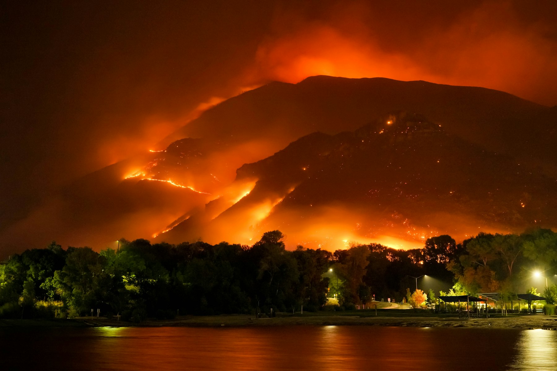 A wildfire burning across a hillside above a community at night