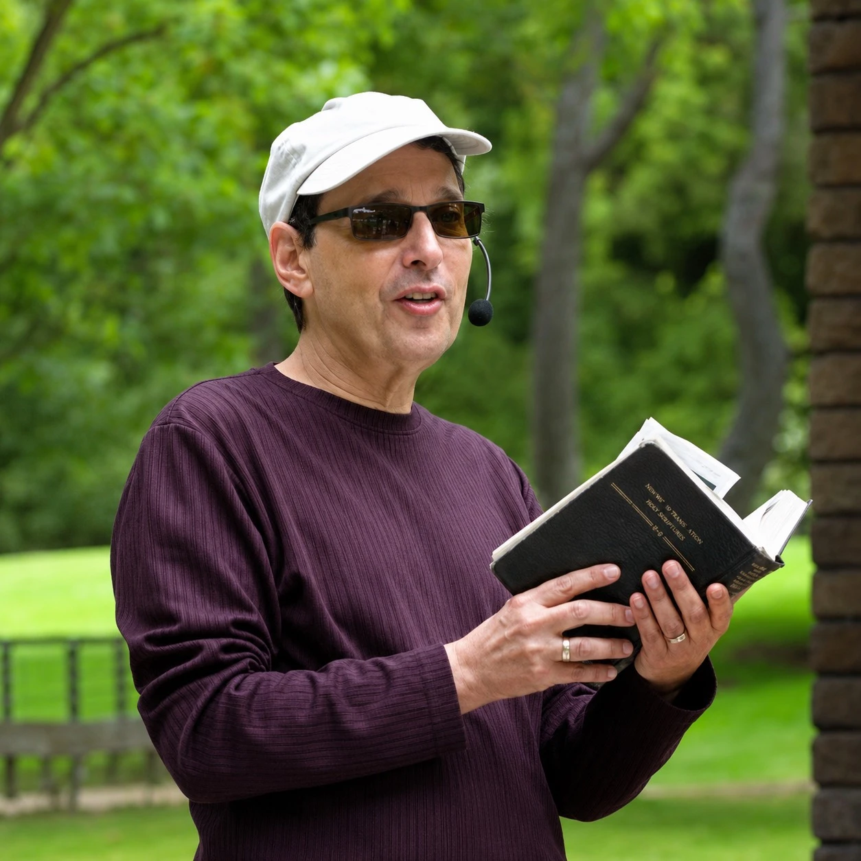 Rabbi Corey Sylvester teaching outdoors with a book and headset microphone
