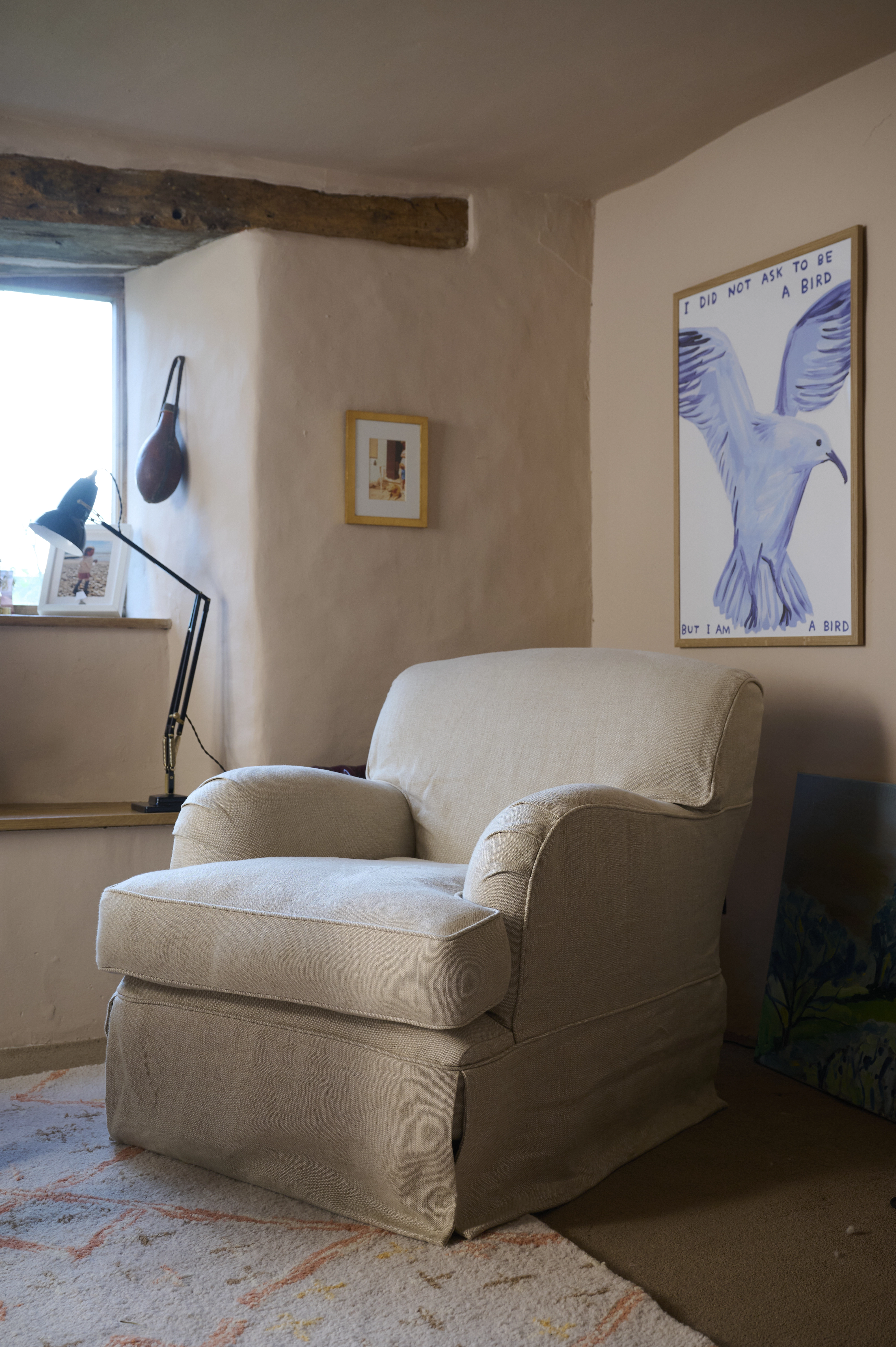 A cosy armchair sits beside a window in a softly lit living room.