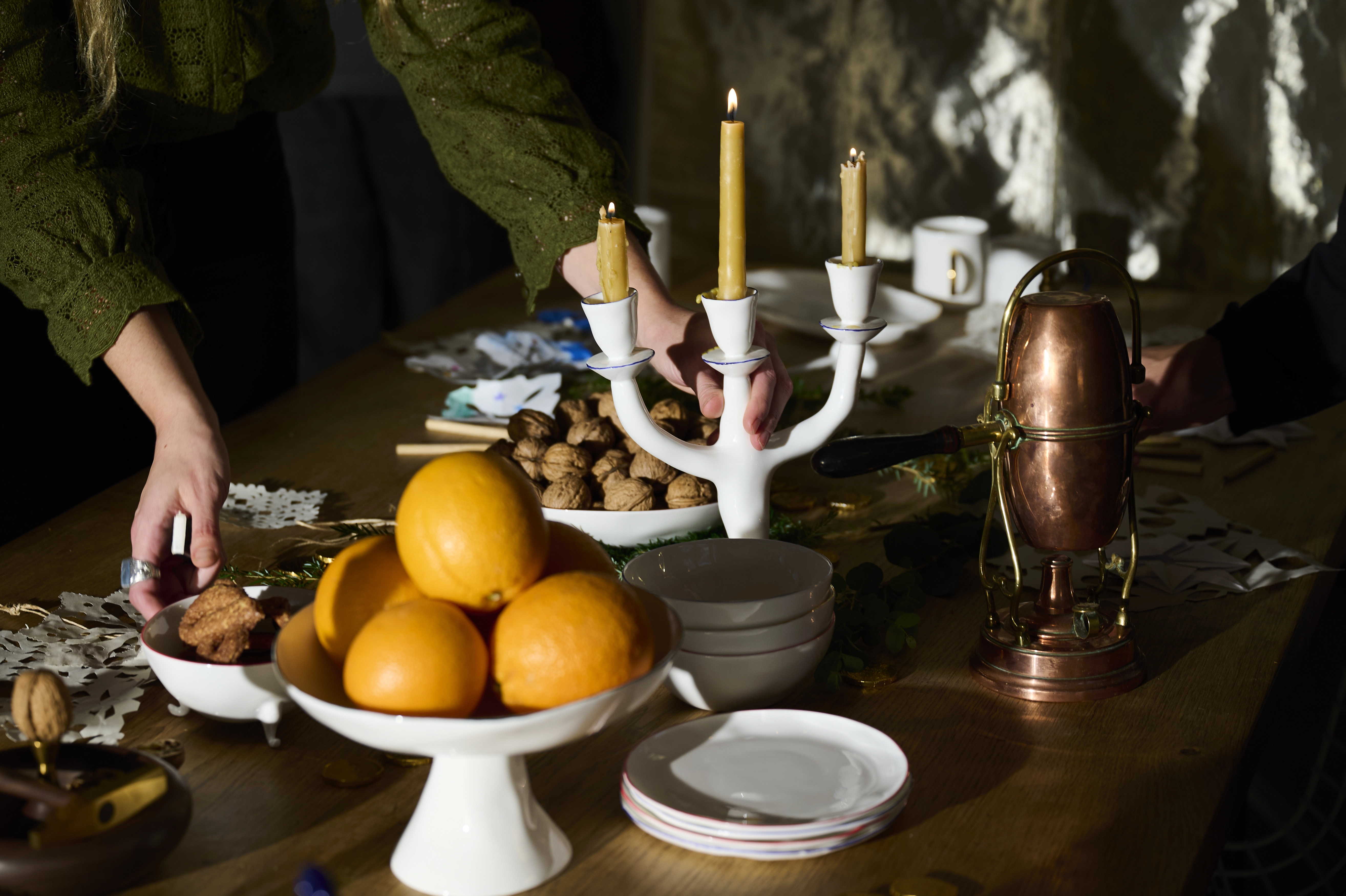 A candlelit table with fruit, tableware, and festive decorations.