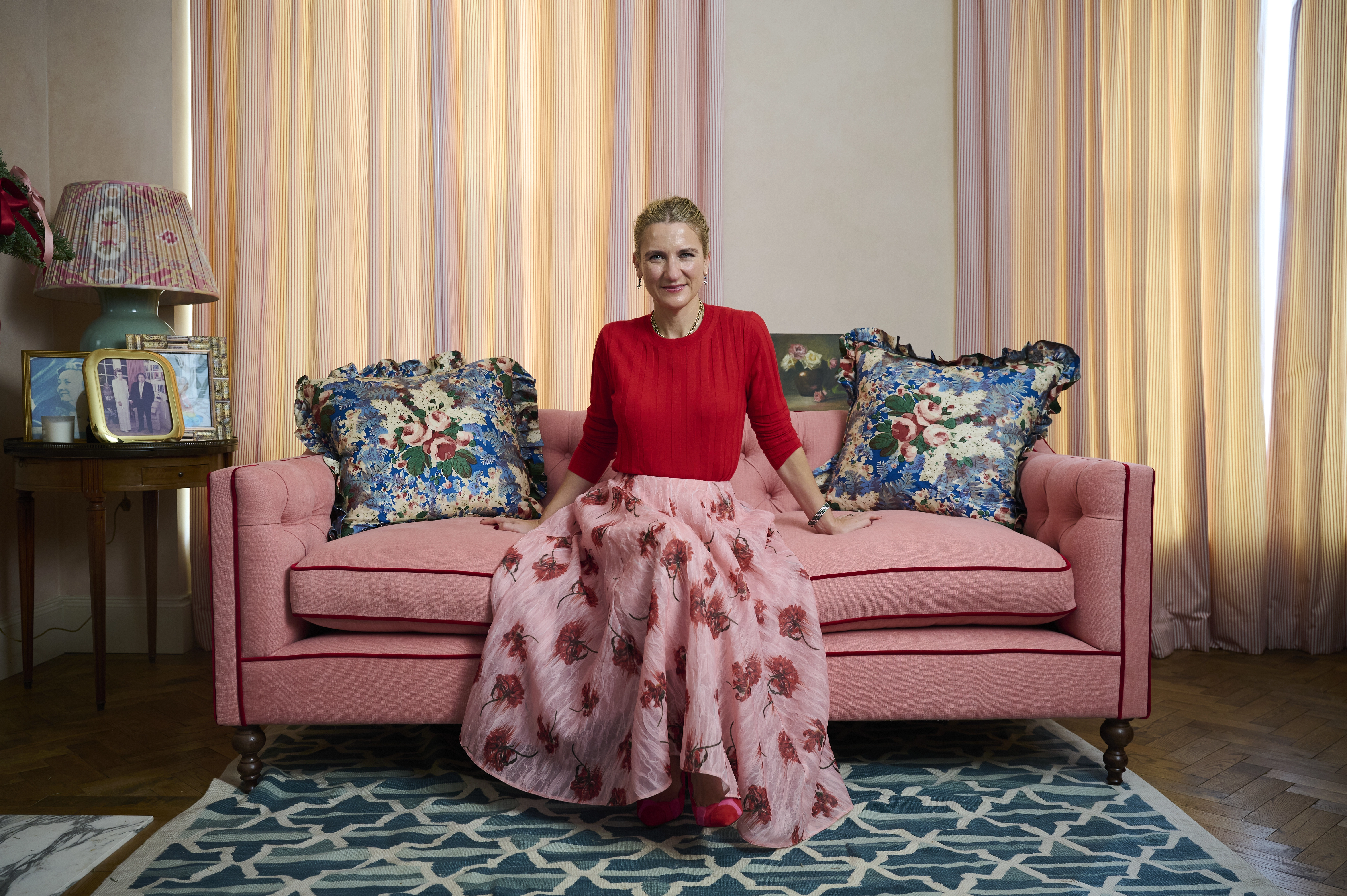 woman sits on a pink sofa in a softly decorated living room.