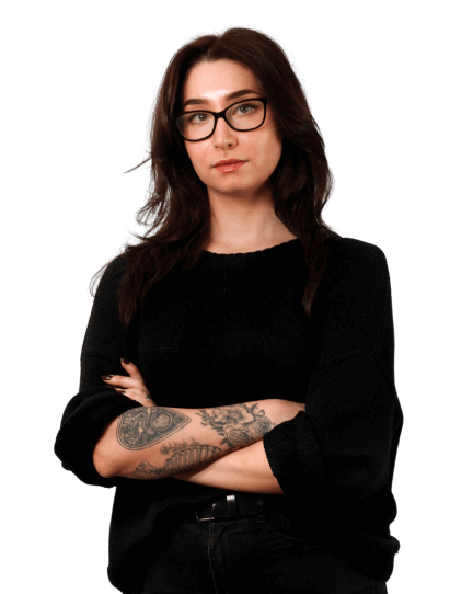  Angie is wearing black jeans, black glasses and a black cardigan as she looks directly into the camera.