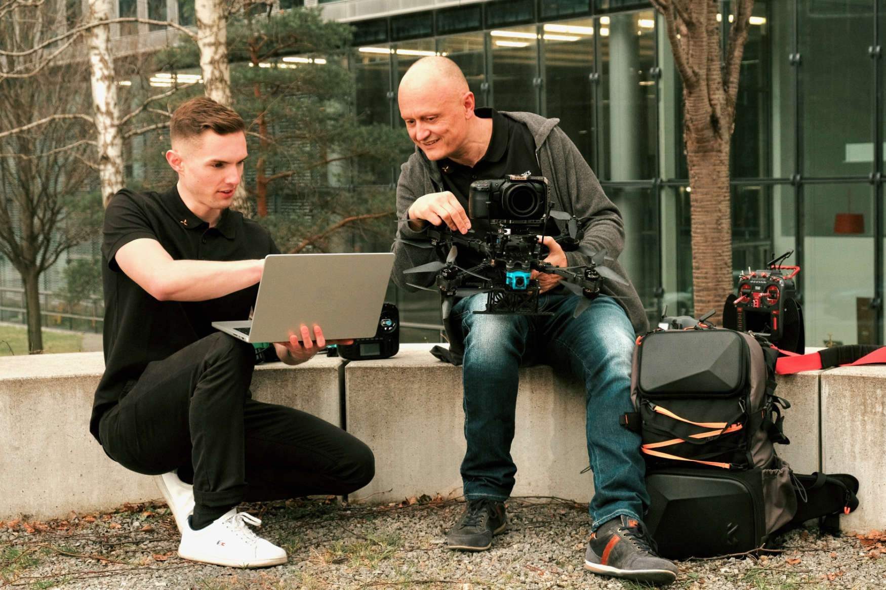 Two persons sitting with drones and a laptop