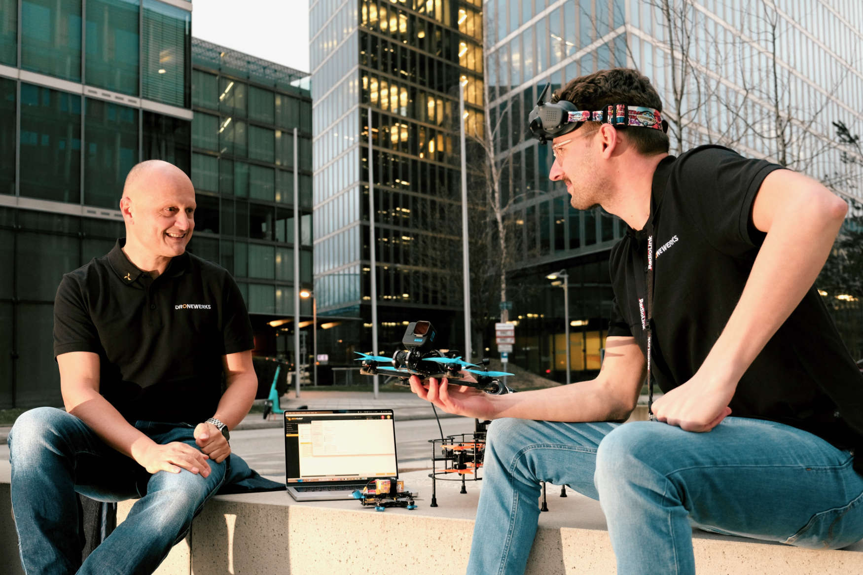 Two men discussing over drones and laptop