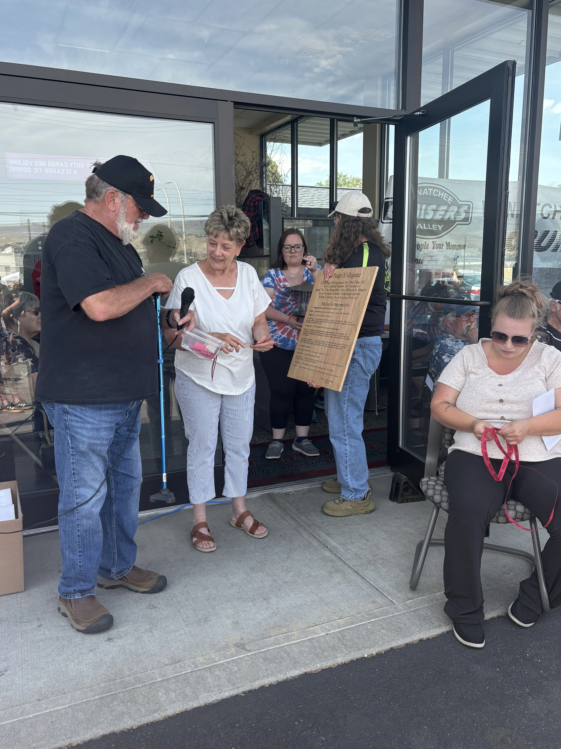 A group of people gathered at the glass entrance of a building for a raffle drawing.
