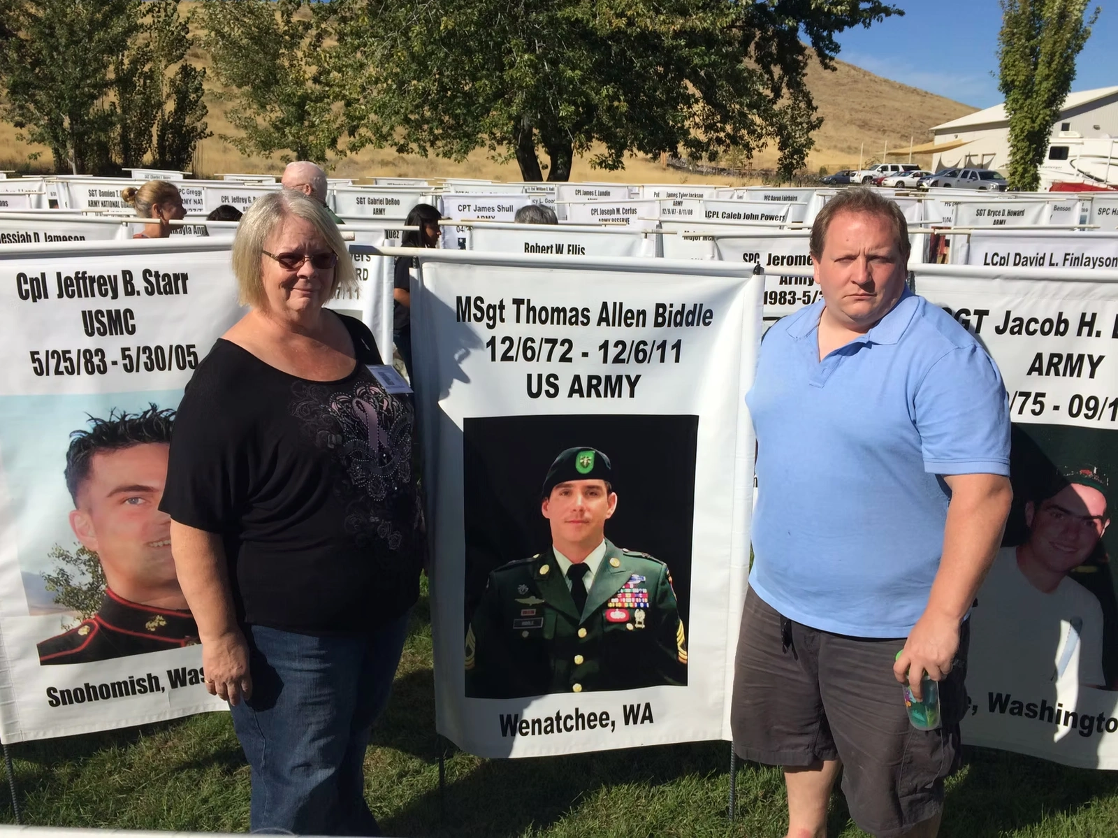 Nancy Brouwers and Chris Biddle standing in front of memorial banner for Thomas A. Biddle.